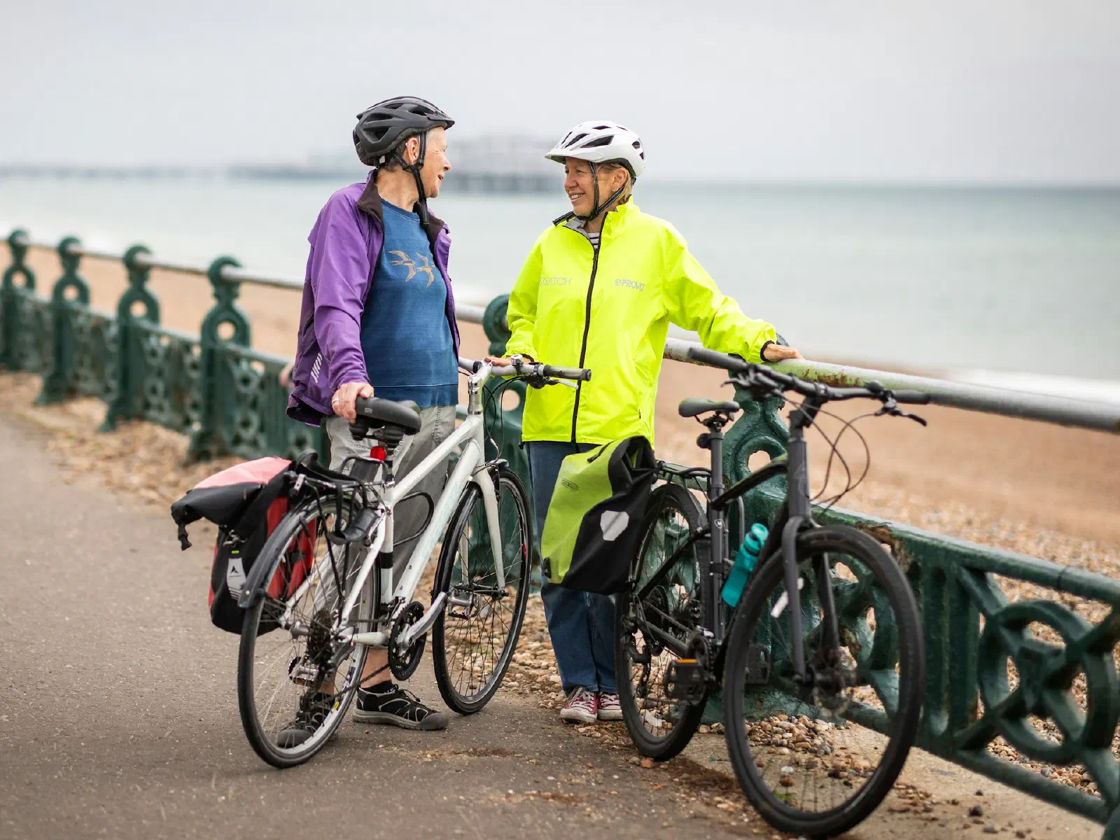 Deux cyclistes discutent à côté de leurs vélos sur une promenade en front de mer.