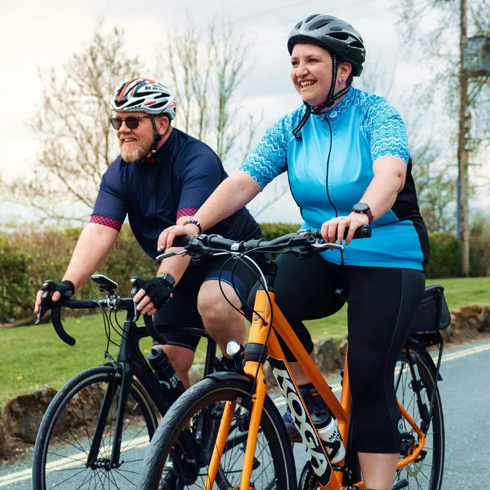 Un homme et une femme en tenue de cycliste roulent sur une route de campagne.