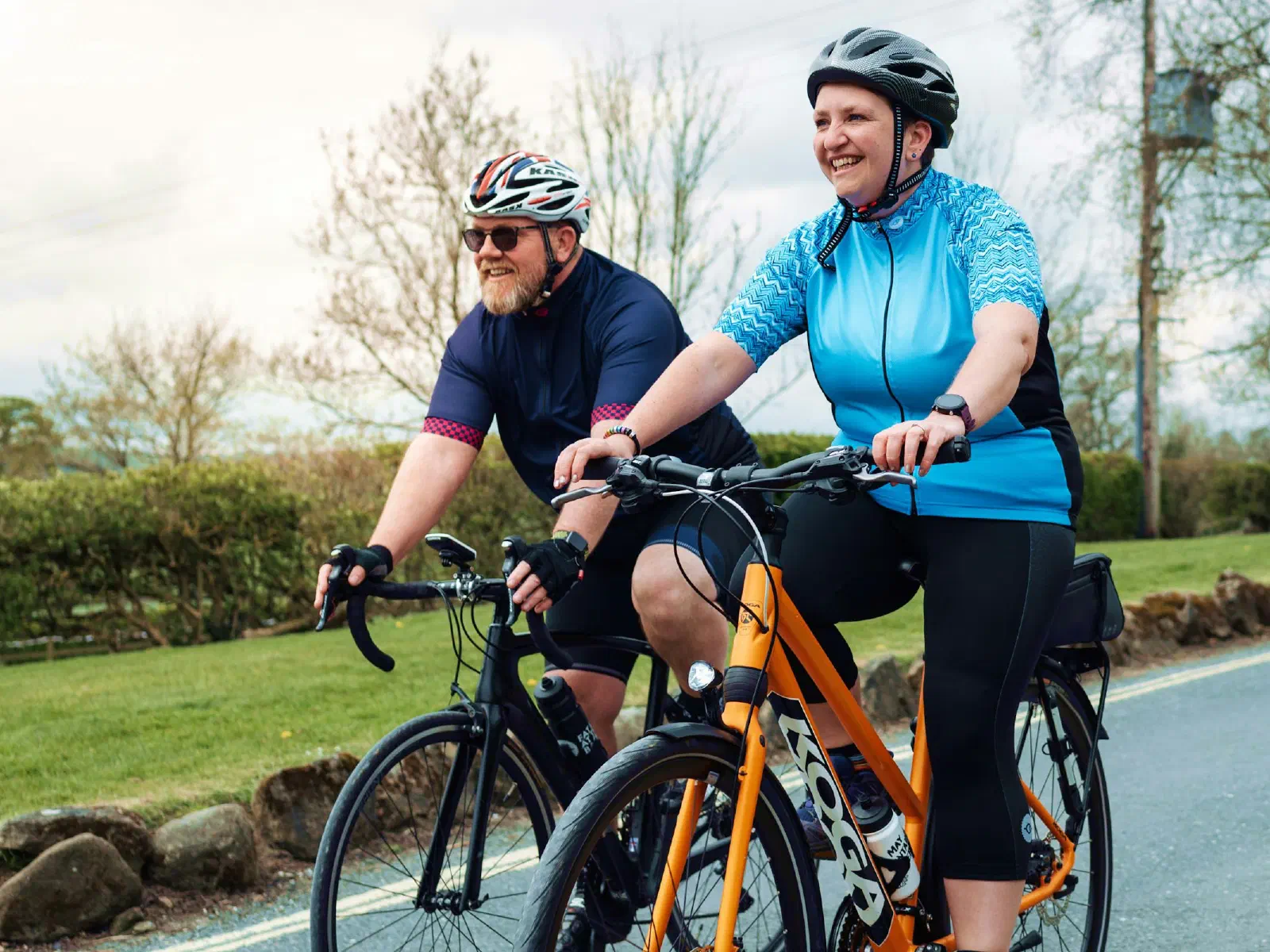 Un homme et une femme en tenue de cycliste roulent sur une route de campagne.